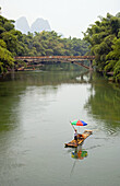 Lone bamboo raft on paddling on the Yulong River in Guilin, China