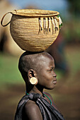 A beautiful Mursi girl with a basket on her head