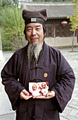 A Taoist monk hold a photograph of cute baby twins