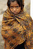 A girl in the streets of Amritsar  She is trying to stay warm in an early cold morning during the winter season