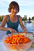 Woman on a houseboat cutting vegetable, Brandenburg, Germany