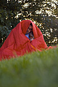 Father and daughter (2-3 years) covered in blanket, English Garden, Munich, Bavaria, Germany