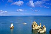 A sailing ship off a rocky coast in the sunlight, Ponta da Piedade, Algarve, Portugal, Europe