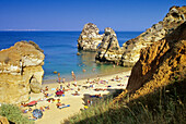 Blick auf Menschen am Strand an der Felsküste, Praia do Camilo, Algarve, Portugal, Europa