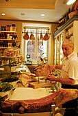 Ein älterer Mann schneidet Prosciutto im Delikatessengeschäft Olio & Convivum, Via S. Spirito, Florenz, Toskana, Italien, Europa