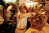 Koch Juan schneidet Schinken im Restaurant Pa amb Oli, Ciutadella, Menorca, Balearen, Spanien