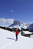 Backcountry skier, snow-covered alpine lodge in background, Grosser Gabler, Eisacktal, Dolomites, Trentino-Alto Adige/Südtirol, Italy