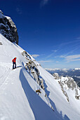 Woman backcountry skiing looking over cornice, Mittenwald, Karwendel range, Bavaria, Germany
