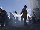 Worshippers swinging incense burning in cans outsiude church in Chichicastenango, Guatemala