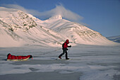 Ski tourer hauling sledge on spring traverse Ny Alesund to Longyearbyen Spitsbergen Island Svalbard Norwegian Arctic