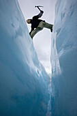 Mountaineer jumbing a crevasse on a glaicier