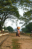 Women carrying a basket over the tracks to the station, Hispaw, Shan State, Myanmar, Burma, Asia
