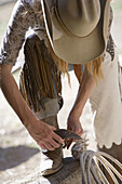 Woman putting on spurs, Lone Mt Ranch, Big Sky, Montana, USA