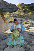 Tarahumara Indian woman weaving a basket outside her house, Urique Canyon, the deepest canyon in the Sierra Tarahumara at 6, 200 feet, is one of six distinct canyons that make up the Copper Canyon Barranca del Cobre, Chihuahua, Mexico