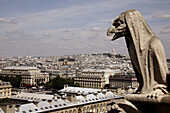 France. Paris. A gargoyle on the Galerie des Chimeres of Notre_Dame Cathedral with the view of city of Paris and Sacre_Coeur Basilica in Montmartre in the background.