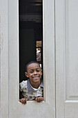 A young boy smiling through a door window.