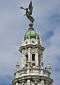 An ornate building tower topped with a statue.