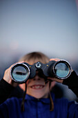 Junge (7 Jahre) blickt durch ein Fernglas, Brixen, Tirol, Österreich