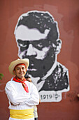 Man in traditional clothes in front of a mural, Oaxaca, Mexico