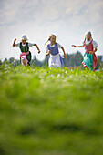 Three girls wearing dirndl in a meadow, Muensing, Bavaria, Germany