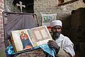 ETHIOPIA  Na’akuto La’ab church, 7 kms from Lalibela, built in a cave  The priest showing some of the church’s treasures: with a manuscript book depicting the miracles of Mary