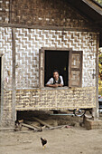Myanmar  Man in the window of a ratan farm house, Myitkyina, a largely Kachin community in north Burma near the Chinese border