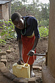 UGANDA  In the home of Najjemba Teopista, Kasaayi village, Kayunga District  13-year-old Faustea taking water harvested from rain which ran from the roof of their house