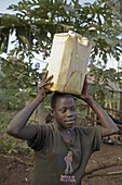 UGANDA  In the home of Najjemba Teopista, Kasaayi village, Kayunga District  Faustea, 13, carrying water