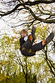 9 yr old boy on swing in autumnul wood, Gloucestershire, UK