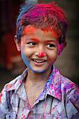 Panjim Goa, India, child covered with colored powder at Holi feast parade