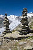 Piled stones to mark the road in the mountains  Valley glacier with its longitudinal moraines of the Glacier Alesht  At the bottom the summits of the Monch, the Junfrau and the Eiger  Berneses Alps  Switzerland