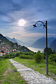 Cobbled path with lantern leading towards Bre, lake Lugano, Lago di Lugano in the background, Monte Bre, Lugano, Ticino, Switzerland