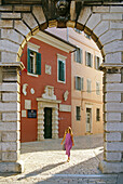 Eine Frau und venezianisches Balbi Tor in der Altstadt von Rovinj, Kroatische Adriaküste, Istrien, Kroatien, Europa