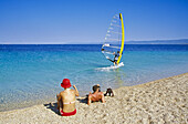 Windsurfer und Menschen am Strand im Sonnenlicht, Goldenes Horn, Insel Brac, Kroatische Adriaküste, Dalmatien, Kroatien, Europa