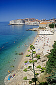 Menschen am Strand vor der Altstadt von Dubrovnik im Sonnenlicht, Kroatische Adriaküste, Dalmatien, Kroatien, Europa