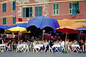 Menschen sitzen unter Sonnenschirmen vor einem Restaurant, Vernazza, Cinque Terre, Ligurien, Italienische Riviera, Italien, Europa