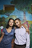 A young man and young woman in front of a wall mural, Berkeley, California, USA