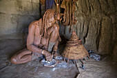 Himba woman shows how to perfume clothes, Namibia