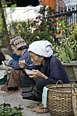 An old woman eating in a market in Asia, Laos