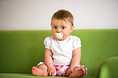 Baby (8 Monate) mit einem Schnuller blickt in die Kamera, Wien, Österreich