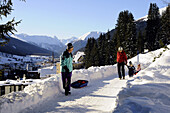 Familie mit Schlitten auf einem verschneitem Weg, Davos, Graubünden, Schweiz