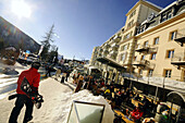 Snowboarder walking trough winterly village, Davos, Grisons, Switzerland