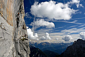 Climber at Schuesselkar rock face in front of white clouds, Tyrol, Austria, Europe