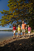 Family walking along the lake shore of Lake Saffelsee, Upper bavaria, Bavaria, Germany