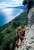 Junge Frau klettert an einer Felswand, Finale, Ligurien, Italien