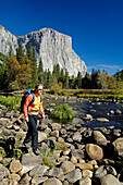 Woman wearing rucksack hiking on stony brookside, Yosemite National Park, California, North America, America