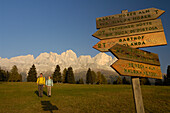 Hikers at a signpost in the light of the evening sun, Rosengarten, Dolomites, South Tyrol, Italy, Europe