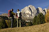 Zwei Bergwanderer betrachten Bergmassiv, Dolomiten, Wolkenstein in Gröden, Trentino-Südtirol, Italien