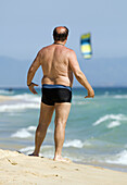 Adult, Adults, back view, Bald, Bathing suit, Bathing suits, beach, beaches, Black hair, Black haired, Color, Colour, Contemporary, Dark Hair, Dark-haired, Daytime, exterior, Full body, Full length, Full-body, Full-length, holiday, holidays, human, Leisur