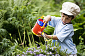 Toddler is watering plants in the garden